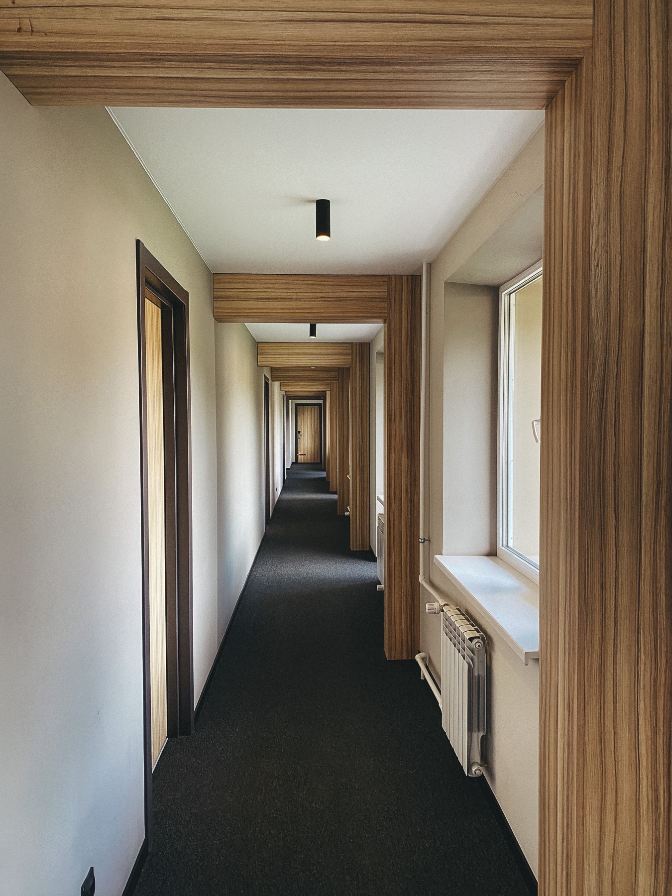 Corridoio d’hotel simmetrico con porte in legno